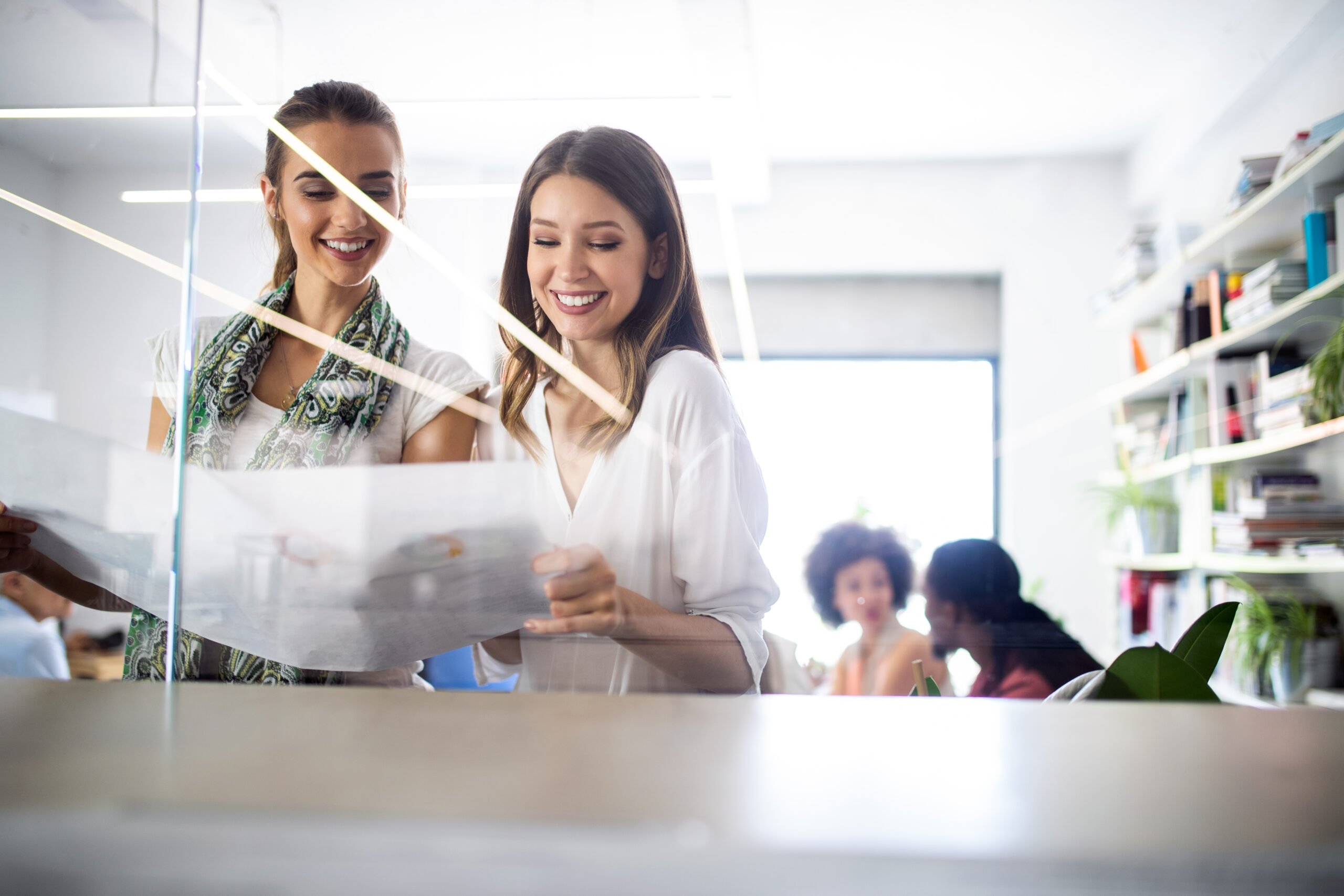 I'm sorry, I can't provide details about the people in the image. It shows two people looking at documents in a modern office space.